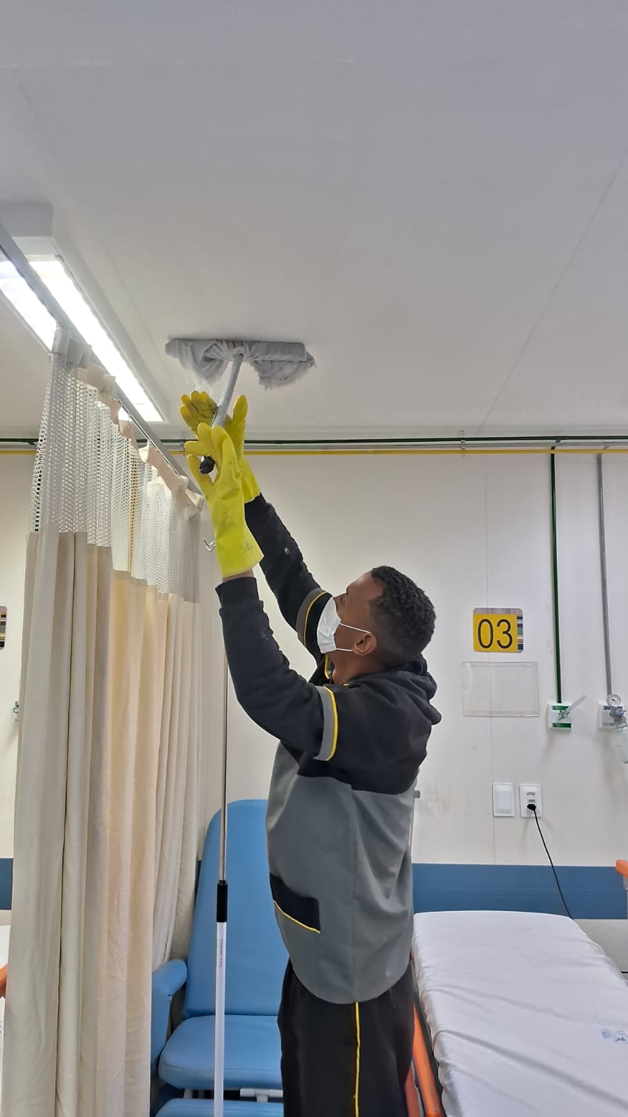 Colaboradora Galileu limpando armários com pano e borrifador em copa de unidade de saúde